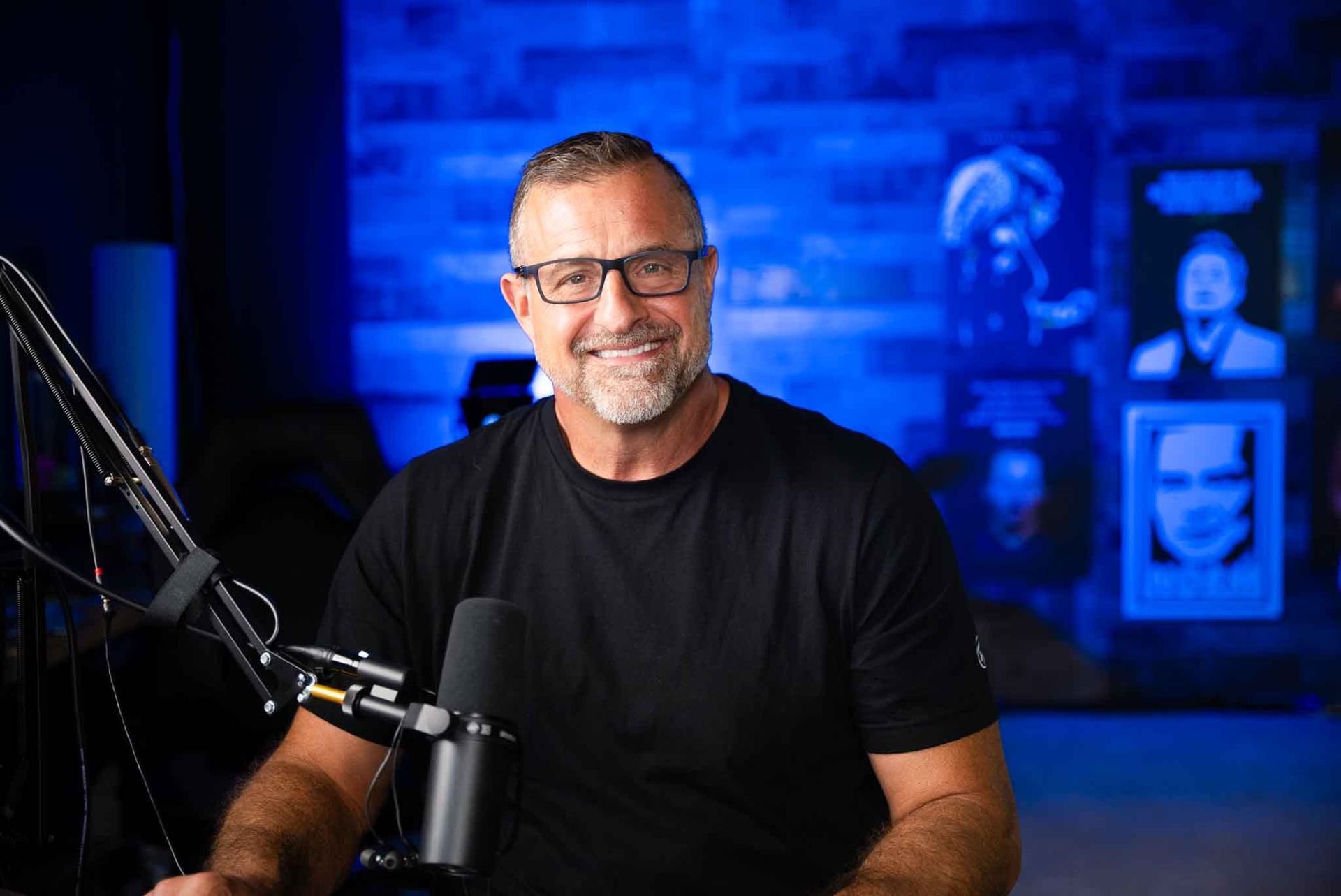 A man wearing glasses is sitting in front of a microphone.