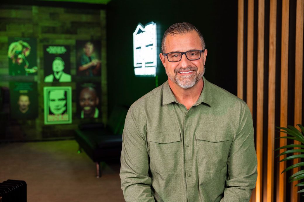 A man wearing glasses and a green shirt is standing in a room.