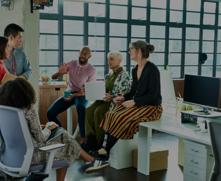 A group of people are sitting around a table in an office having a meeting.