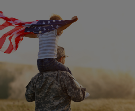 A man in a military uniform is carrying a child on his shoulders.