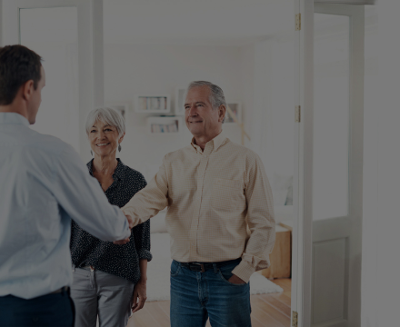 A man and woman are shaking hands with a man in a room.