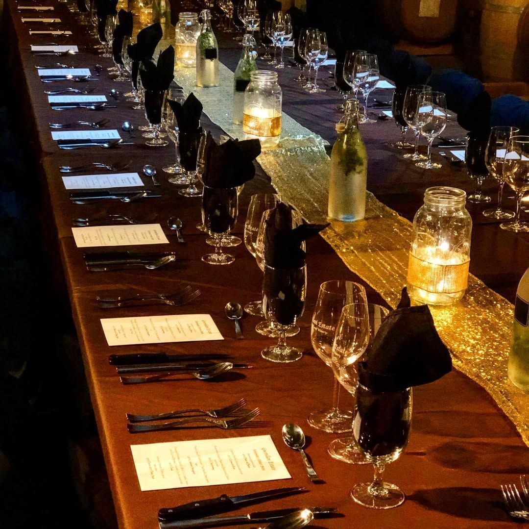 A long table set for a dinner party with wine glasses and silverware