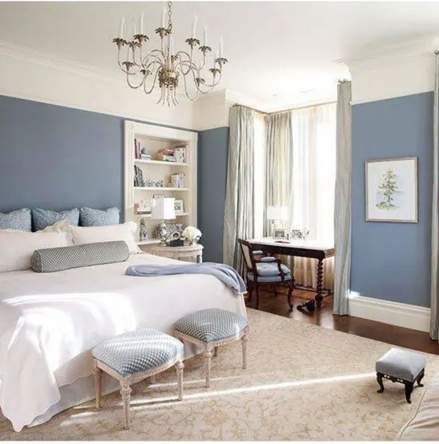 Bedroom with blue walls, a white bed, beige rug, and a desk near the window.
