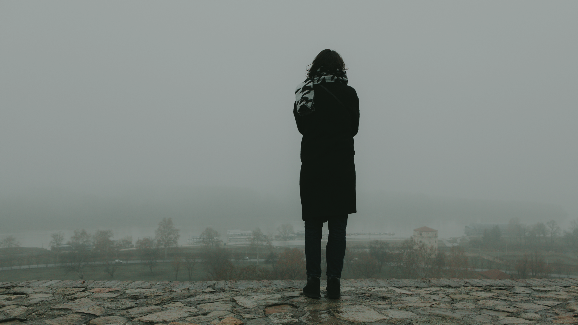 a woman in a black coat is standing in the fog representing dissociative disorders at Healing Our Trauma KC