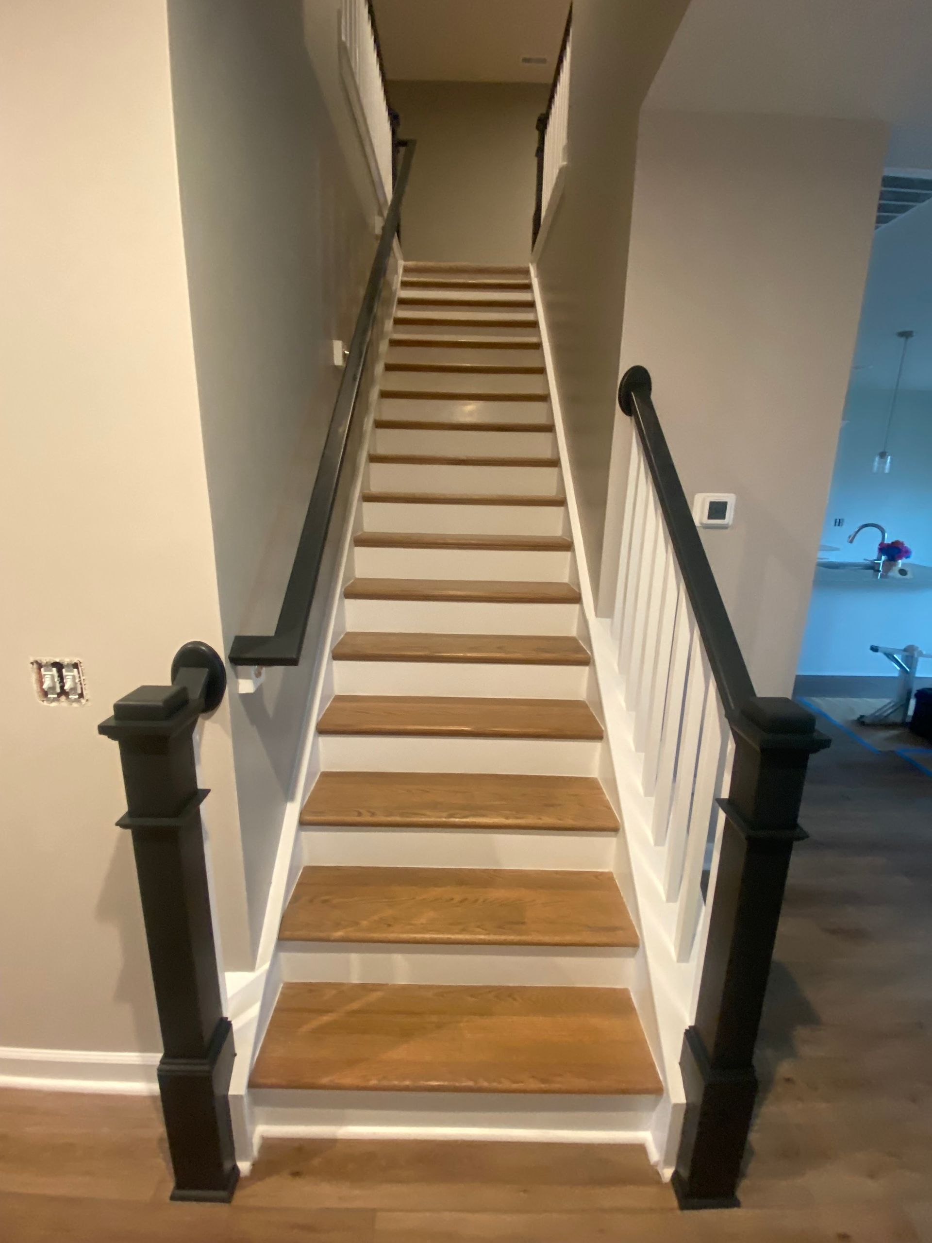 A staircase with wooden steps and a black railing in a house.