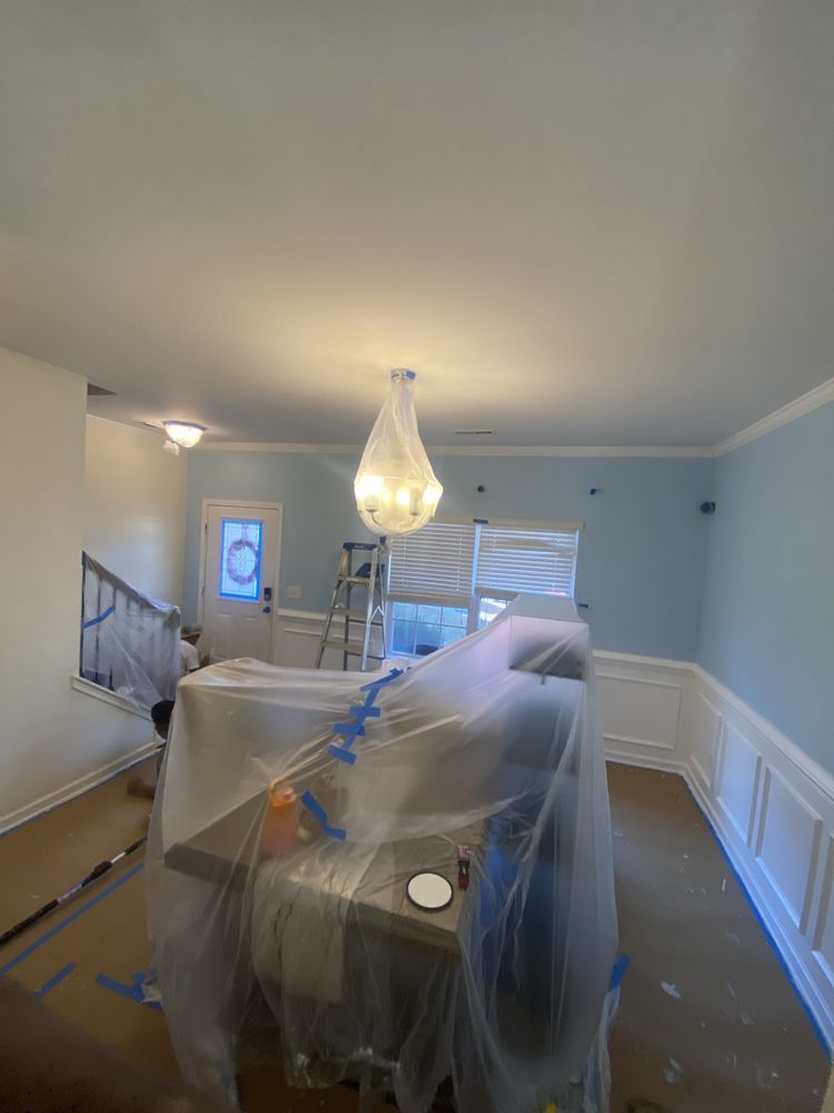 A living room is being painted and covered in plastic.