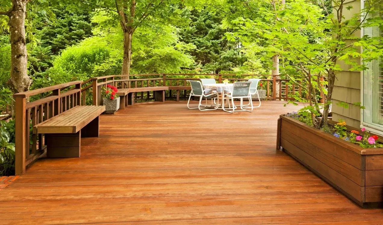 A wooden deck with a table and chairs and a bench.