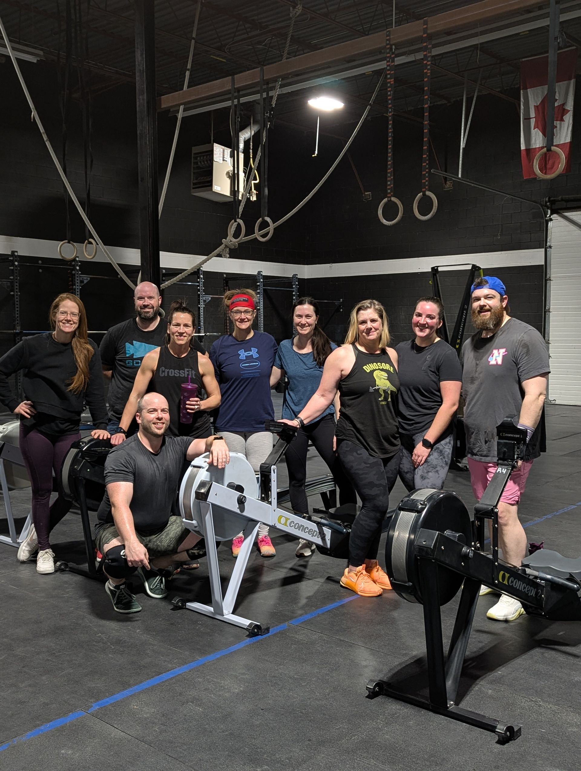 CrossFit Oshawa coach helping beginners with scalable ring rows while supportive community members c