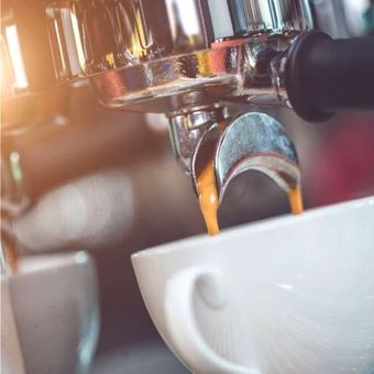 Un primer plano de una cafetera vertiendo café en una taza.