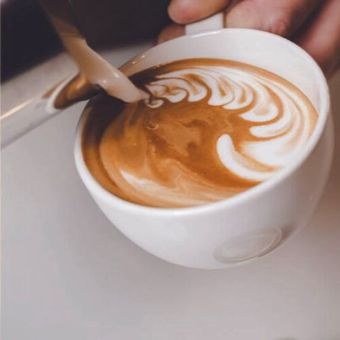 Una persona está sirviendo una taza de café con una cuchara.