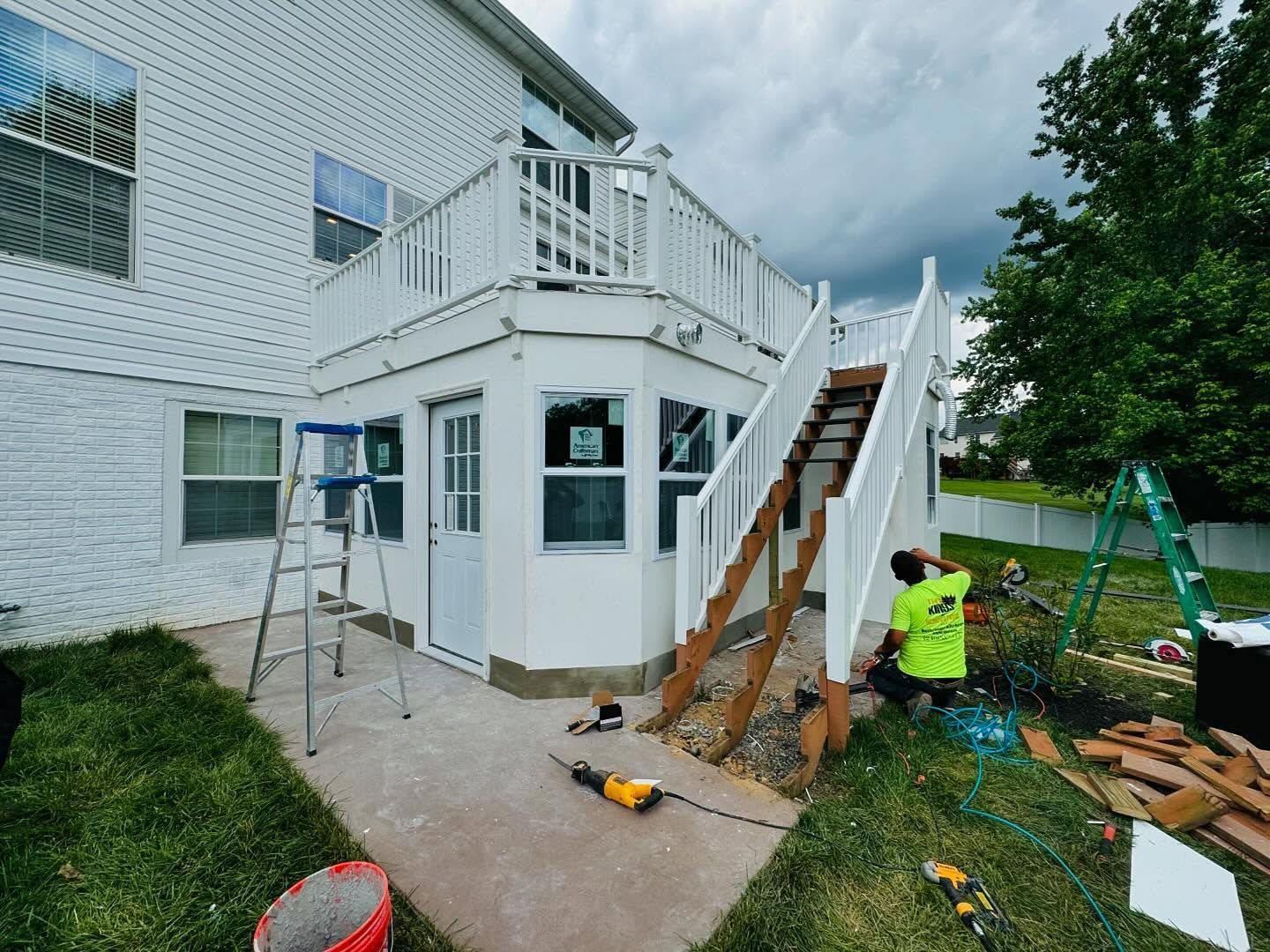 House exterior with deck under construction; worker is visible.