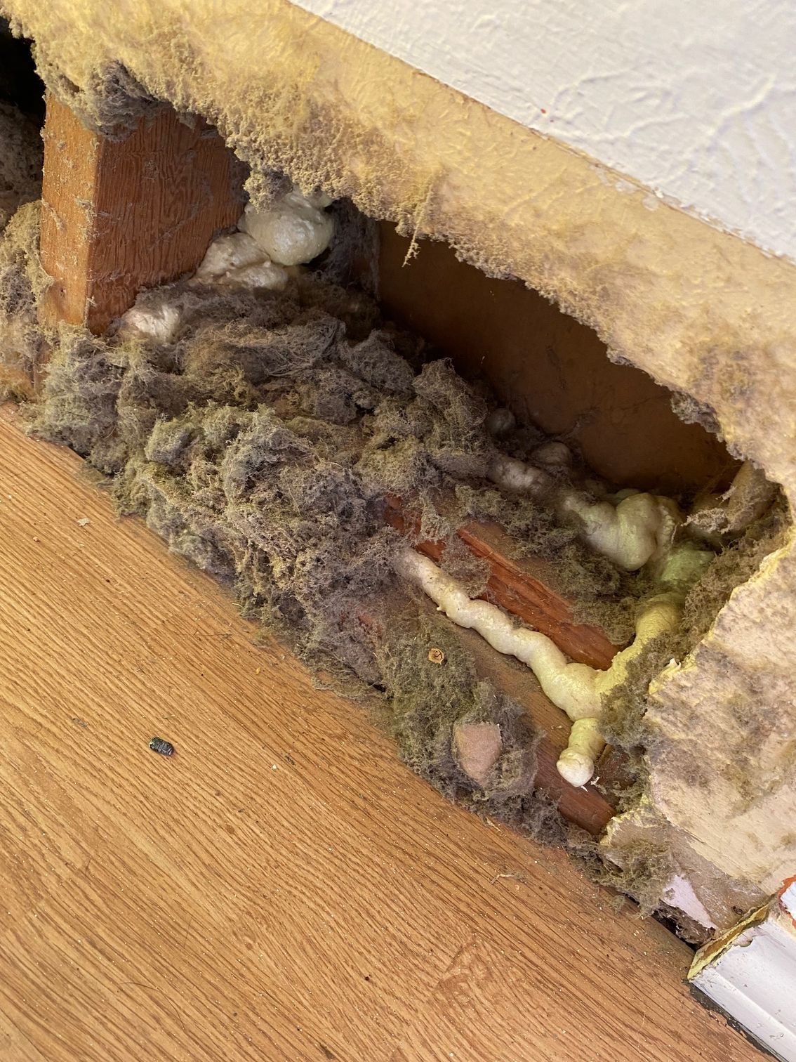 Hole in wall reveals insulation, brick, and foam.