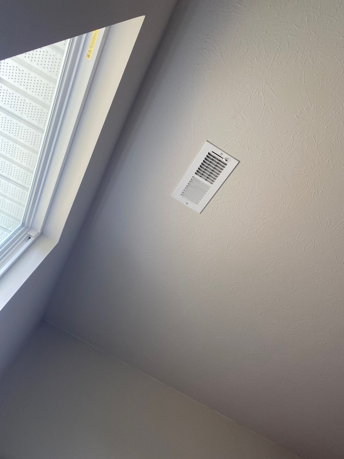 White ceiling with air vent and window with blinds. White ceiling with air vent and window with blinds.