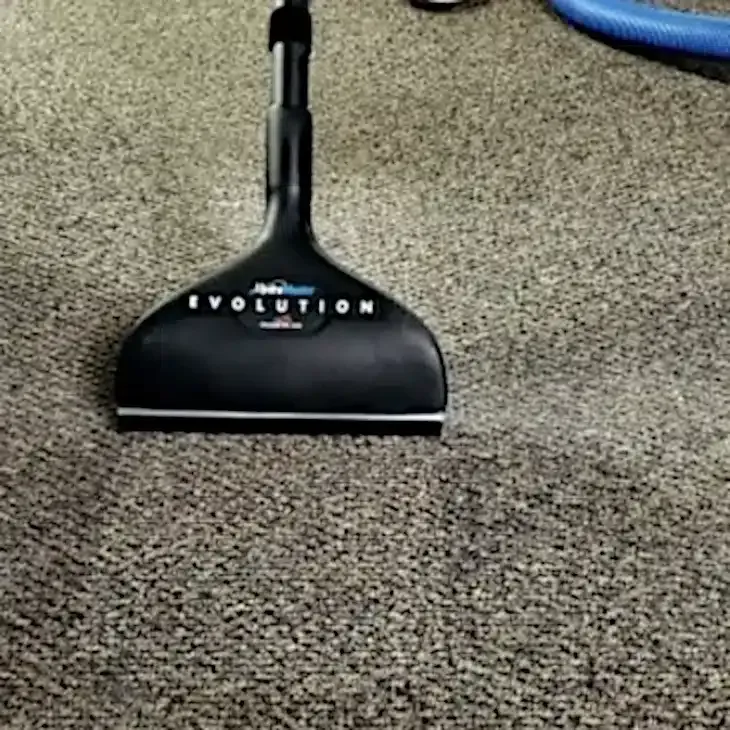 Black vacuum head on gray carpet.