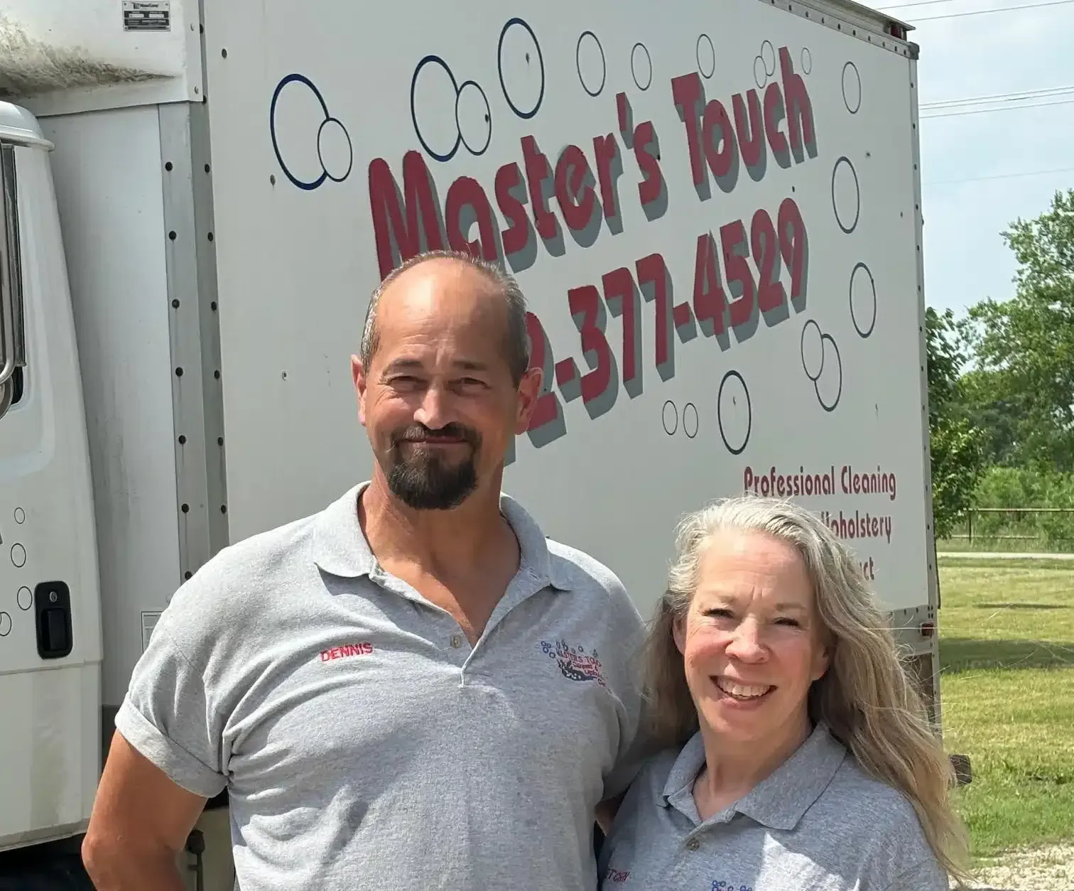 Two people standing in front of a truck, logo reads 