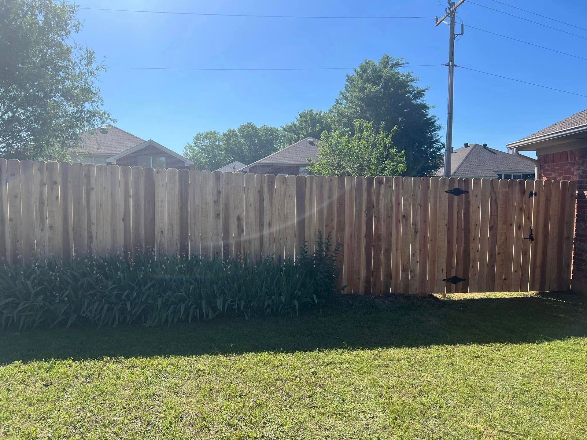 A man is installing a metal fence in a backyard.