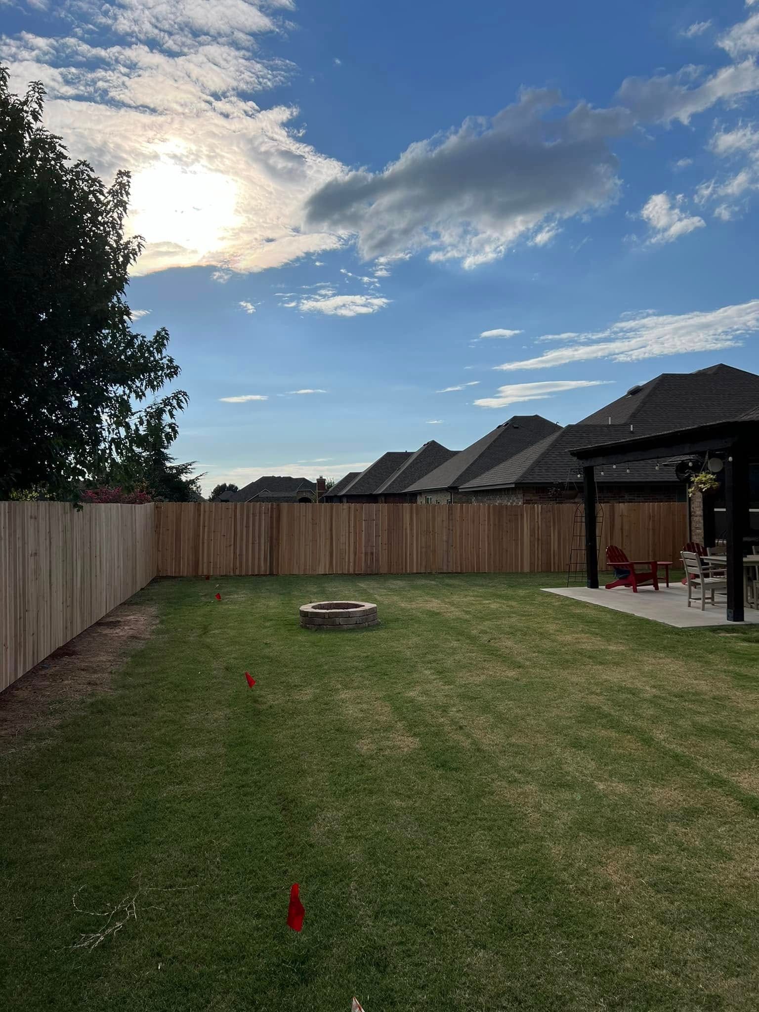 A backyard with a wooden fence and a fire pit.