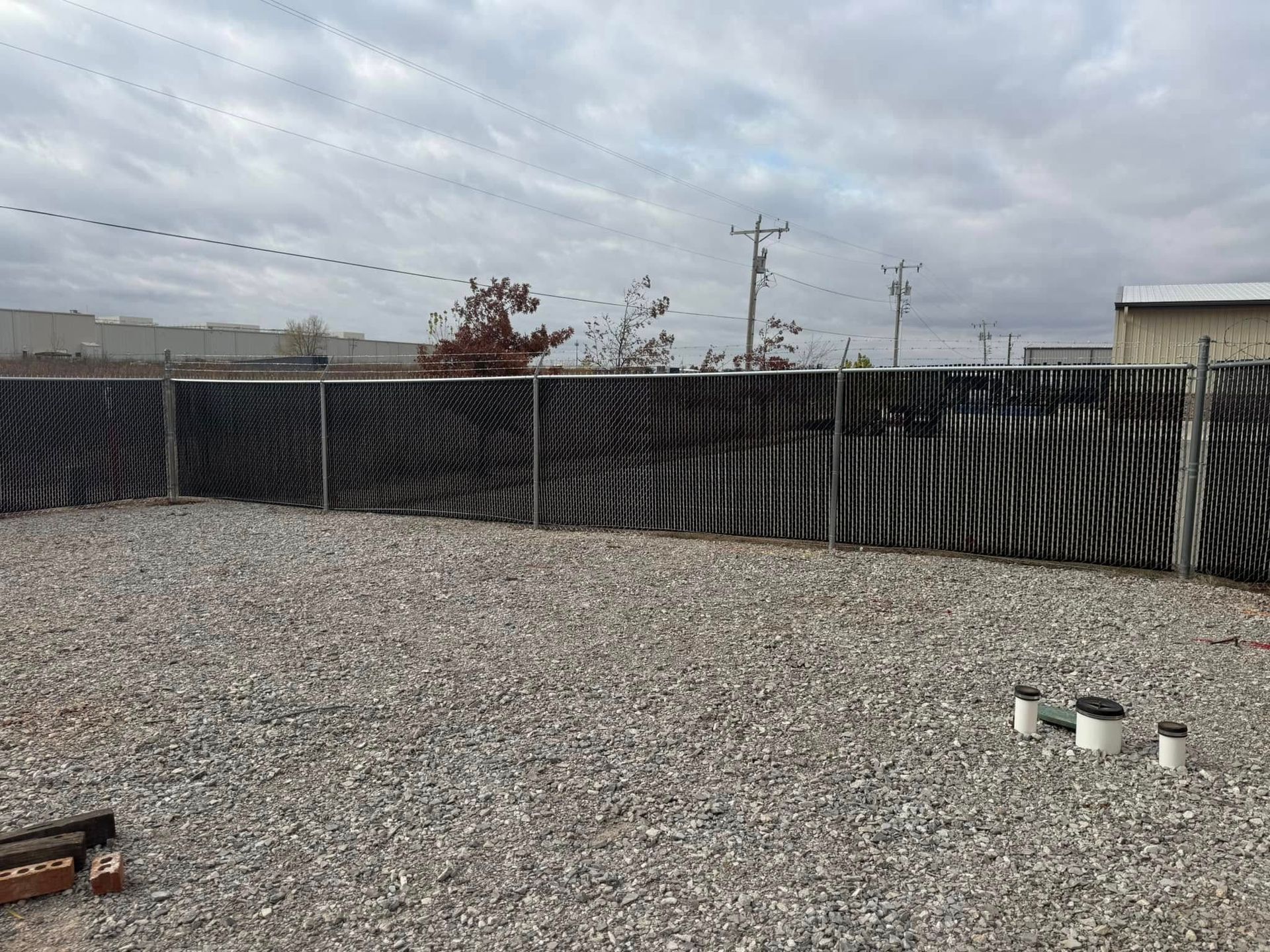 A man is installing a metal fence in a backyard.