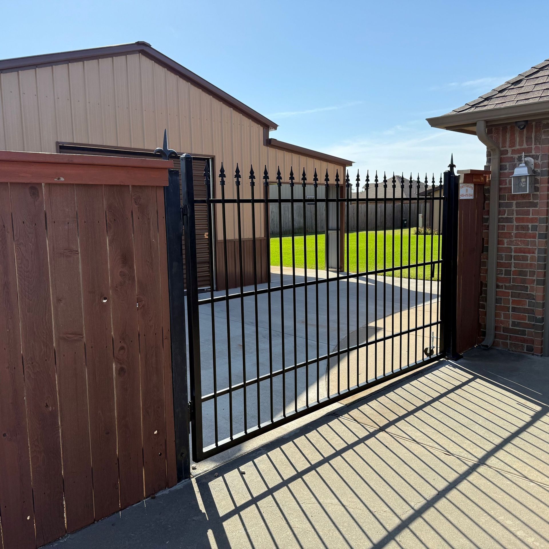 A wrought iron gate with a wooden fence behind it