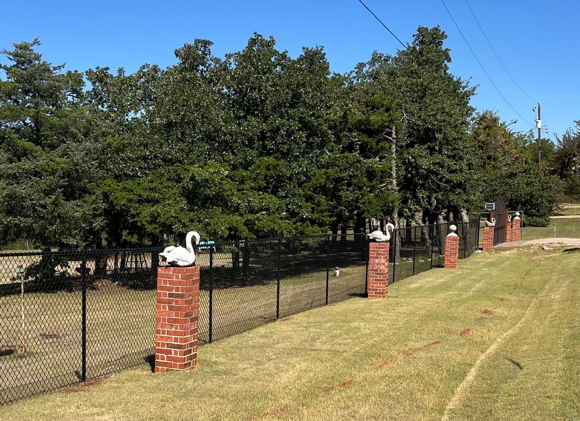 A fence with a swan on top of a brick post