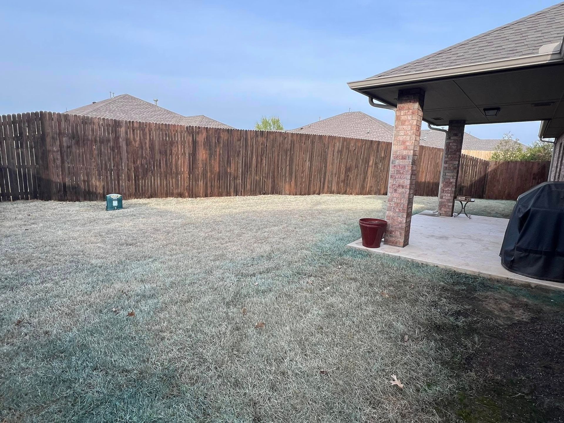 A backyard with a wooden fence and a pavilion.