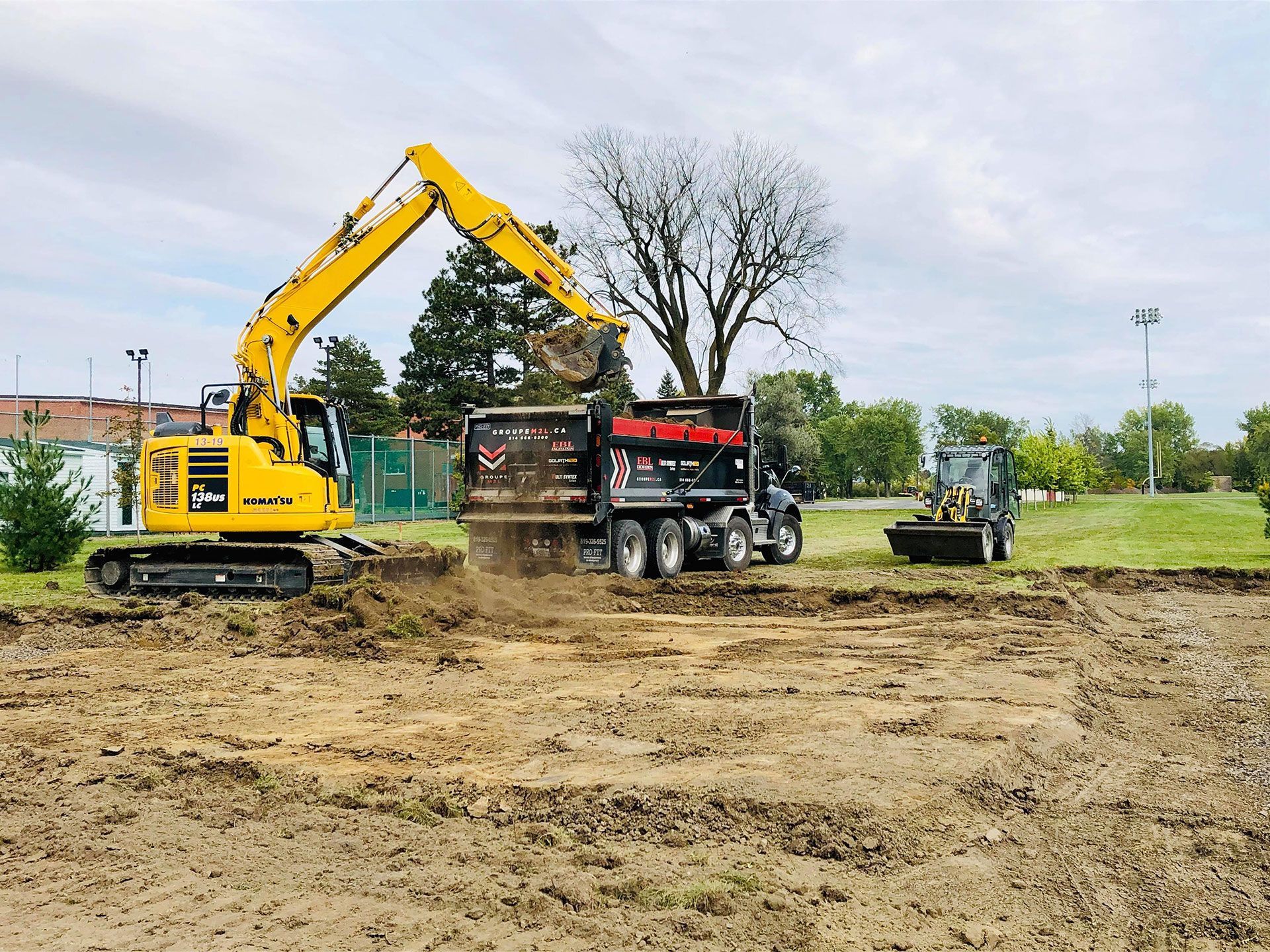 Une excavatrice jaune charge de la terre dans un camion à benne basculante.
