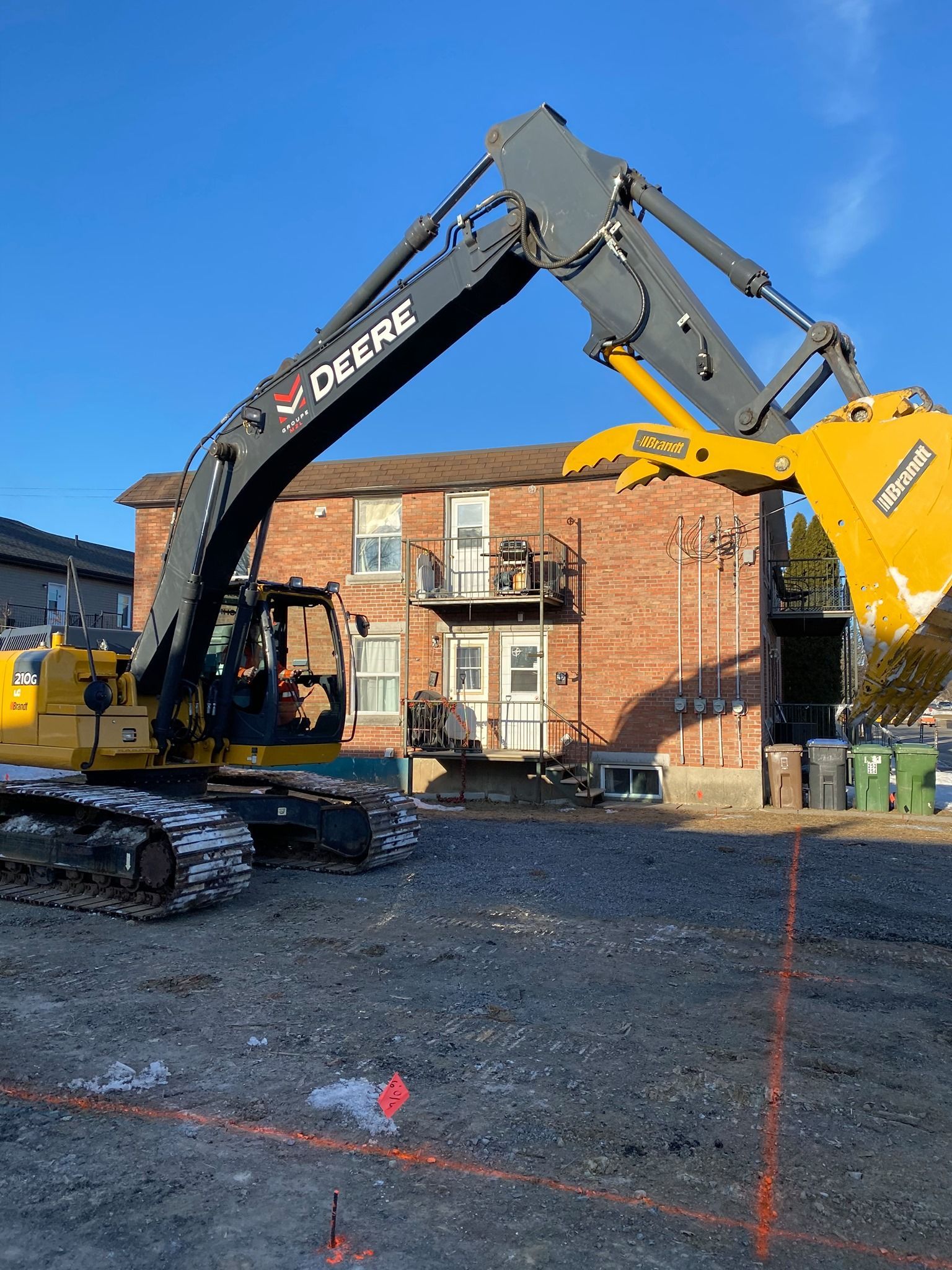 Une grande pelle jaune est garée devant un bâtiment en brique.