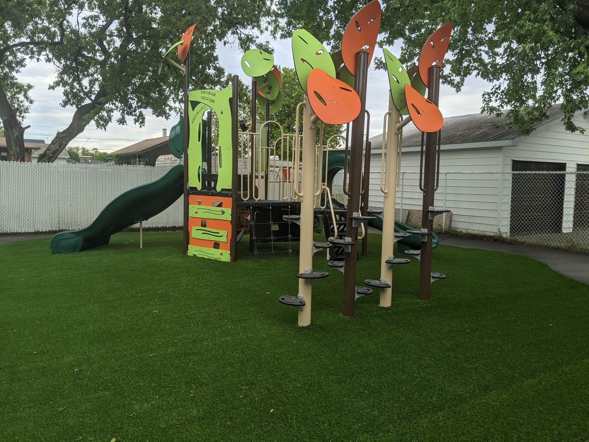 Une aire de jeux colorée avec un toboggan et des escaliers dans une cour.