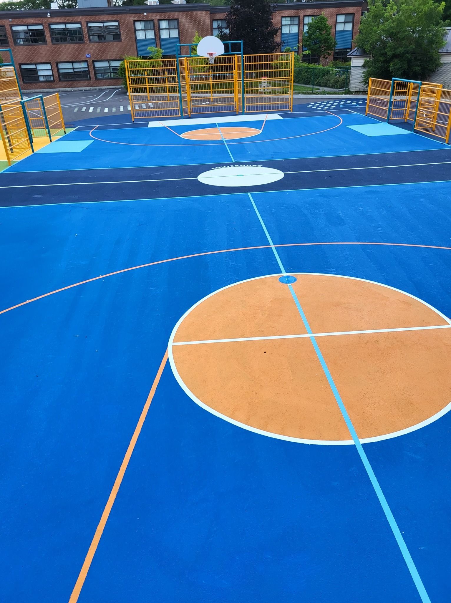 Un terrain de basket bleu et orange devant un immeuble