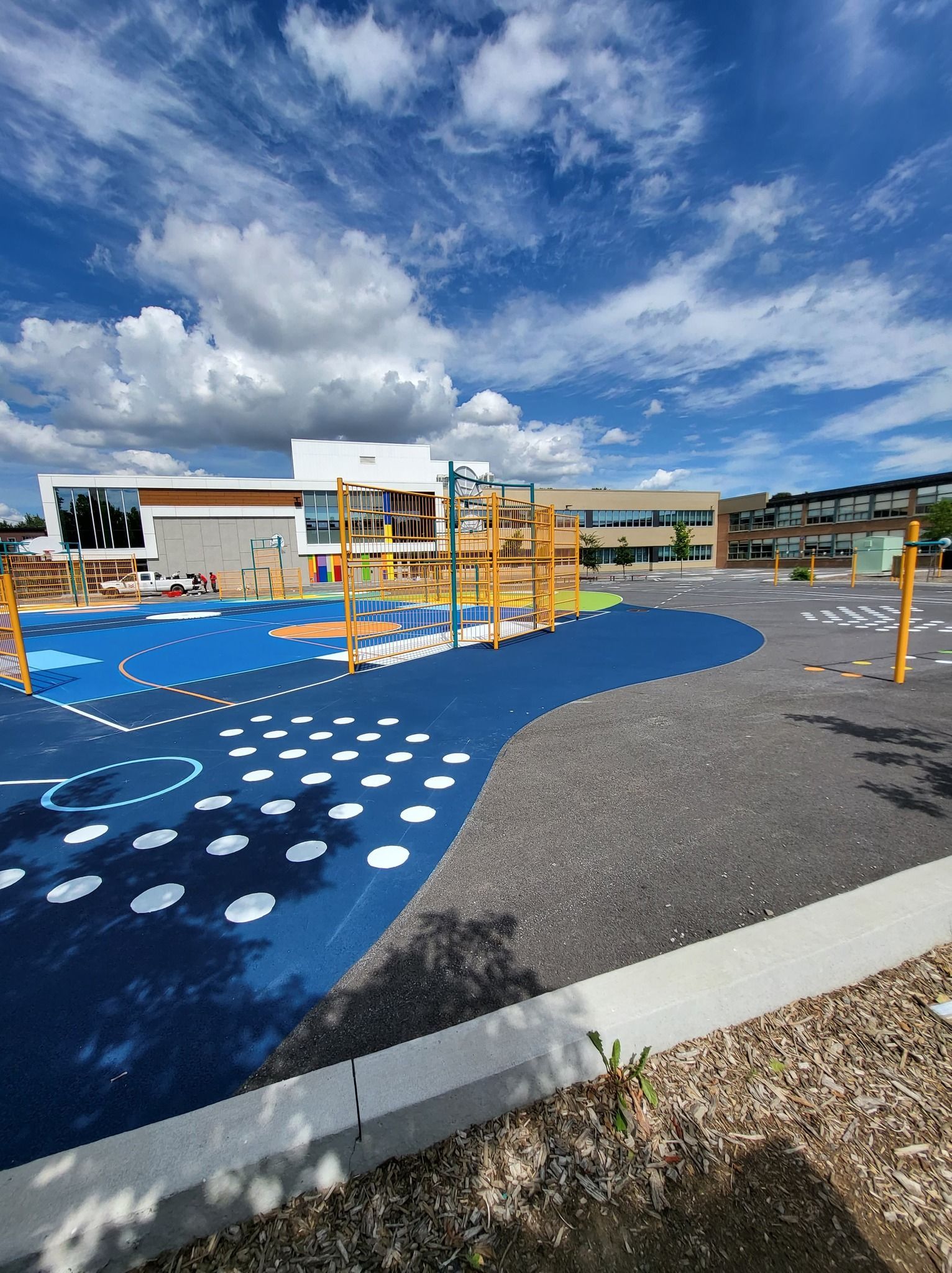 Une aire de jeux avec un bâtiment en arrière-plan par une journée ensoleillée.