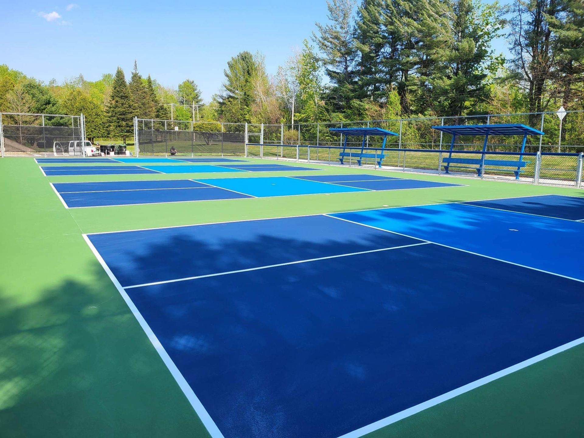 Une rangée de courts de tennis bleus et verts avec des arbres en arrière-plan