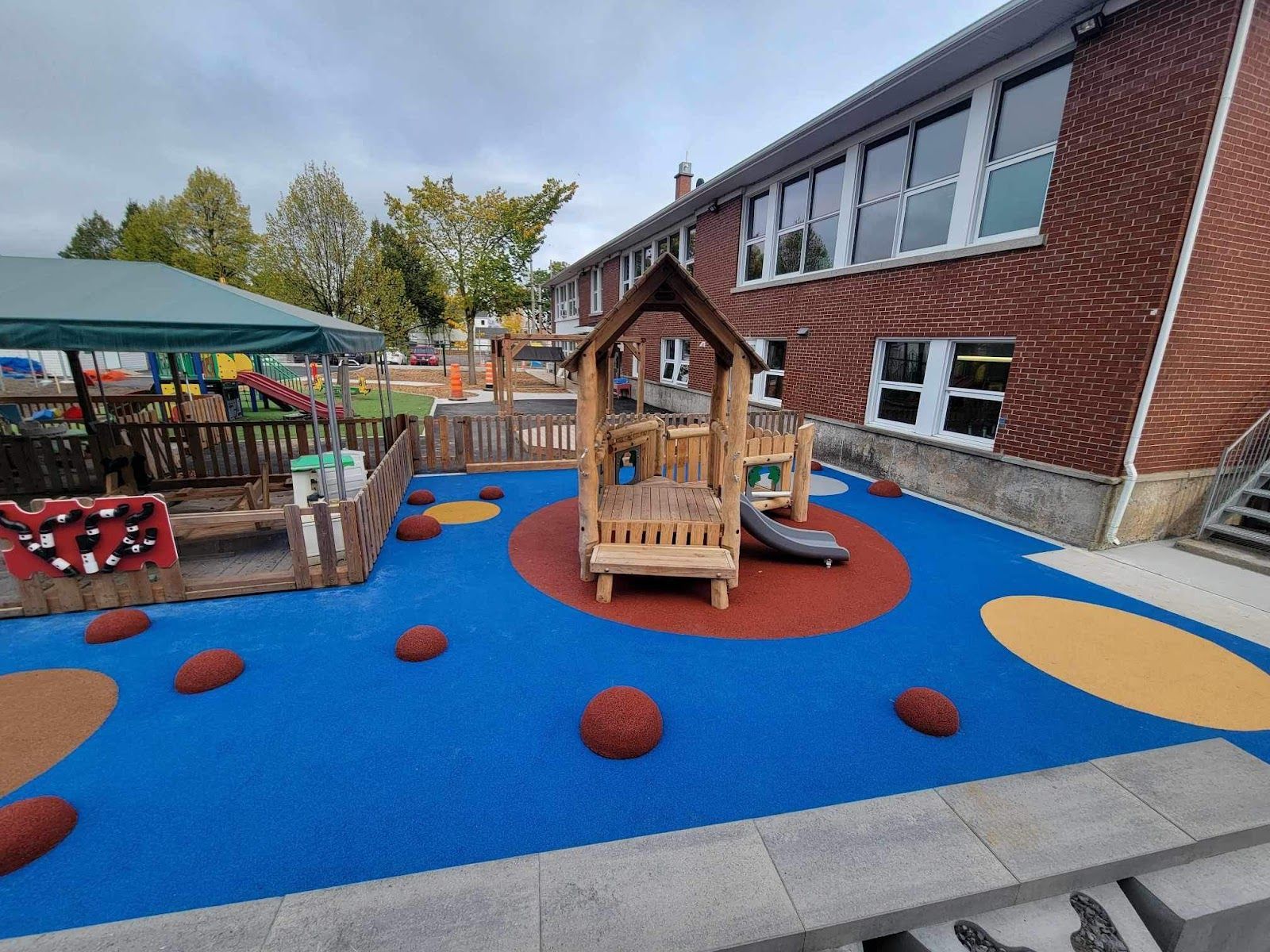 Il y a une aire de jeux devant un bâtiment en brique.