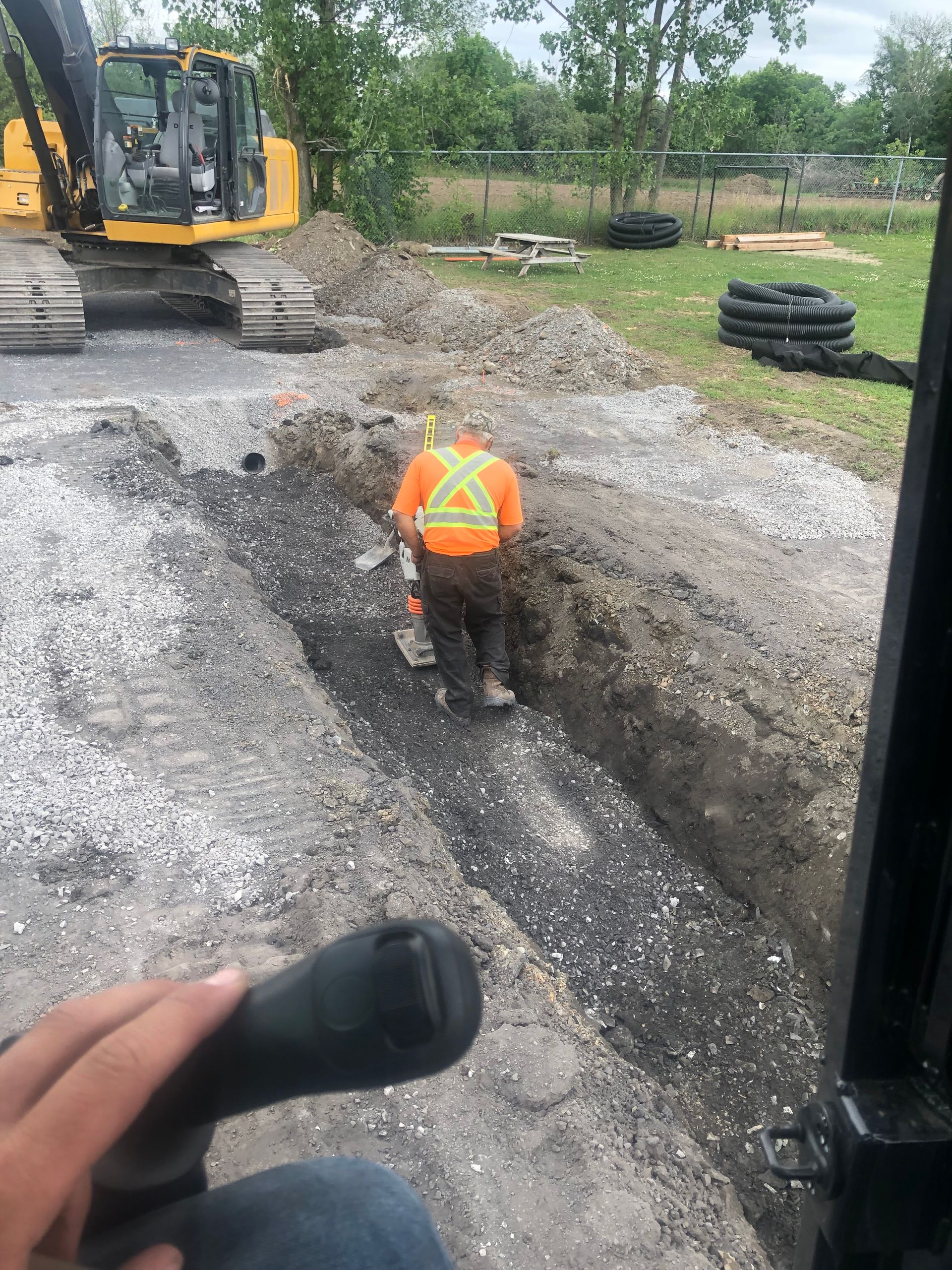 Un homme vêtu d'un gilet orange creuse un trou dans le sol.