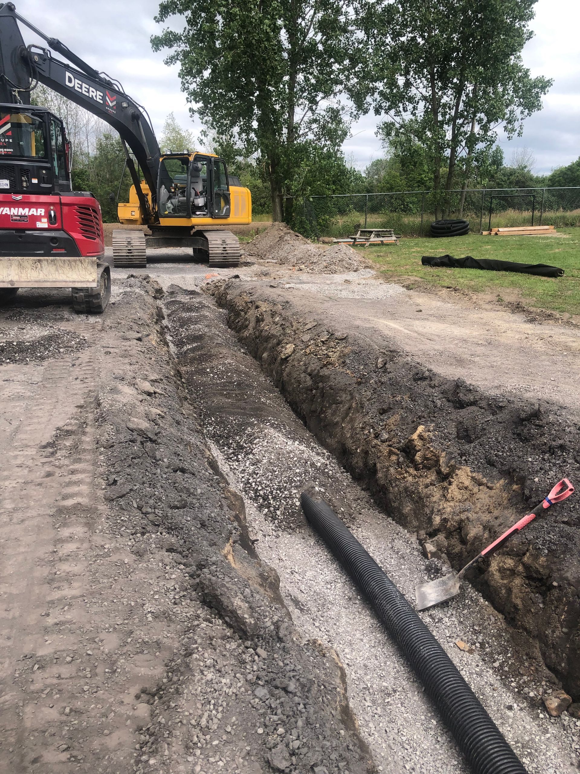 Quelques tracteurs creusent une tranchée dans la terre.