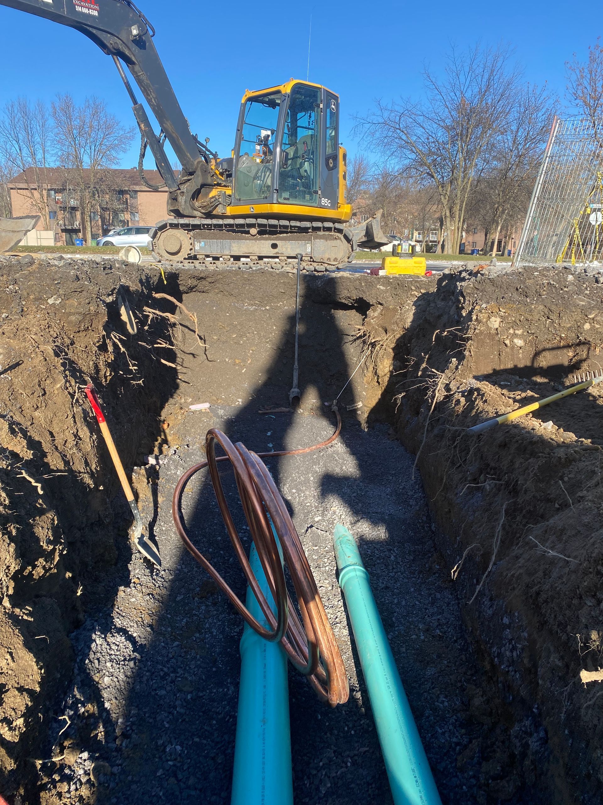 Une excavatrice jaune creuse un trou dans le sol.