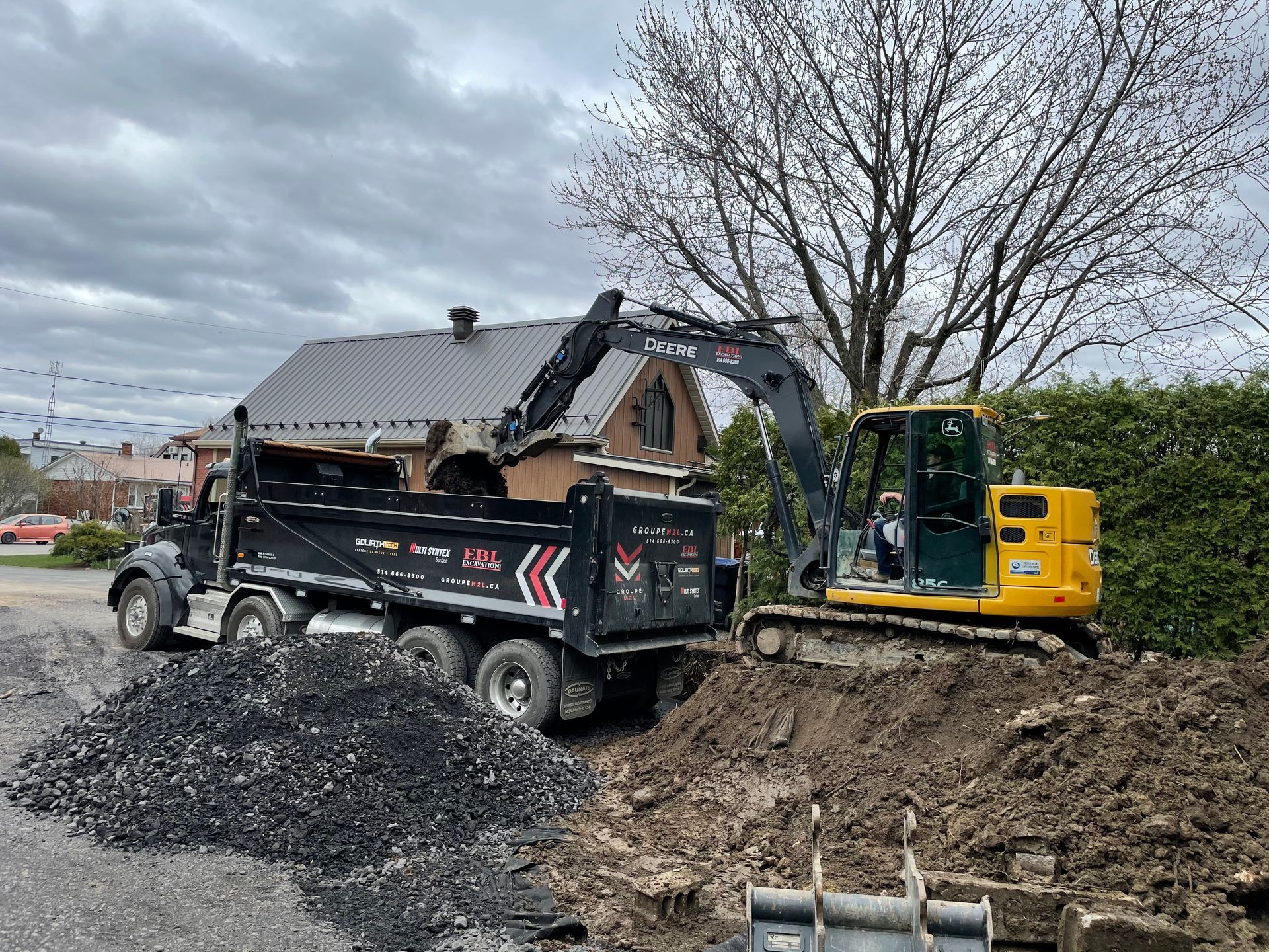 Un camion-benne est chargé de terre à côté d'une excavatrice.