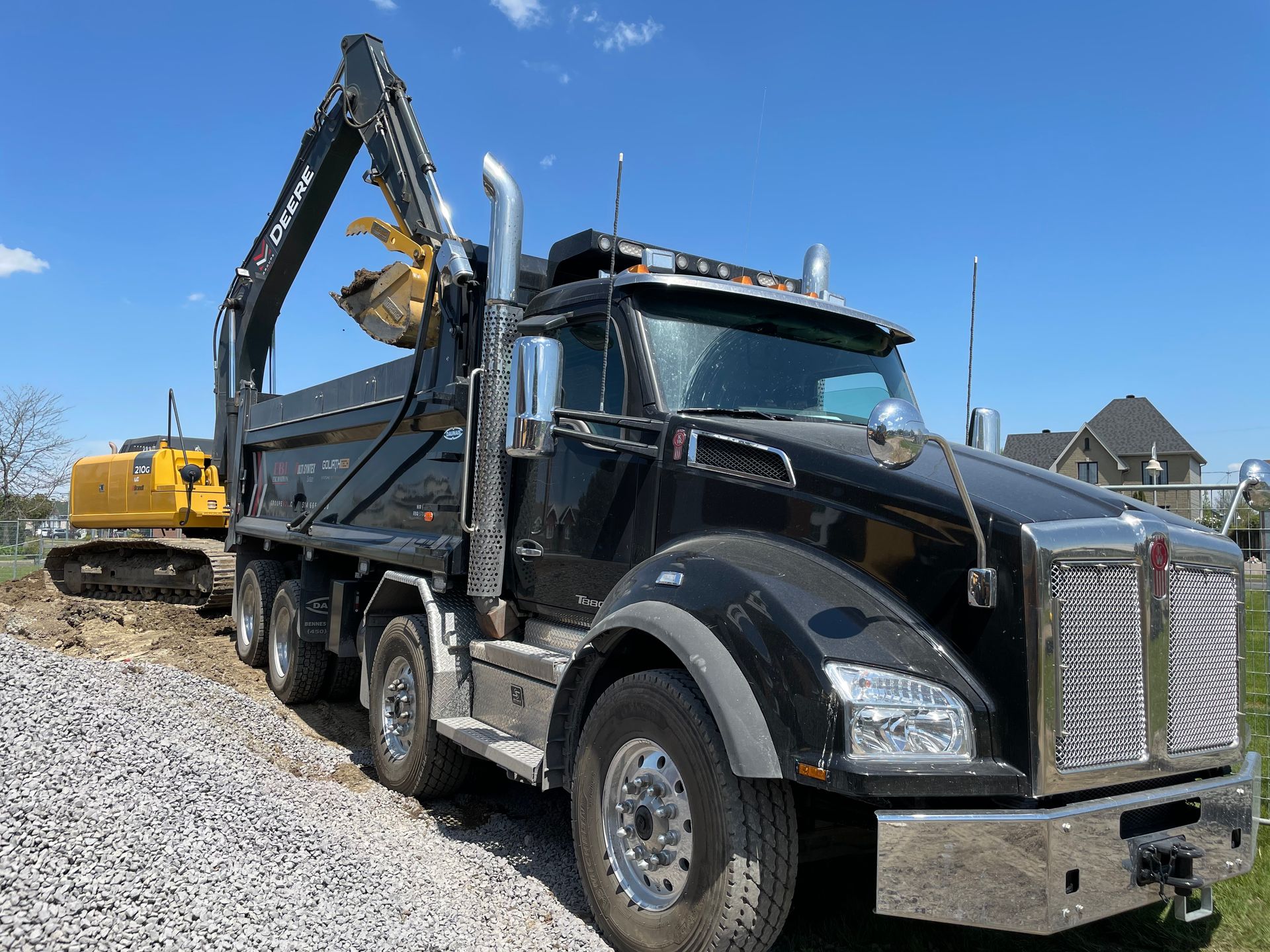 Un camion-benne noir est garé à côté d'une excavatrice jaune.