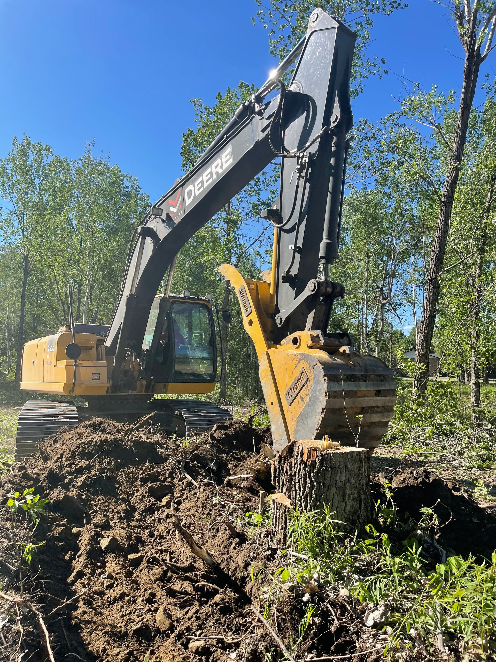 Une grosse pelle creuse un trou au milieu d'une forêt.