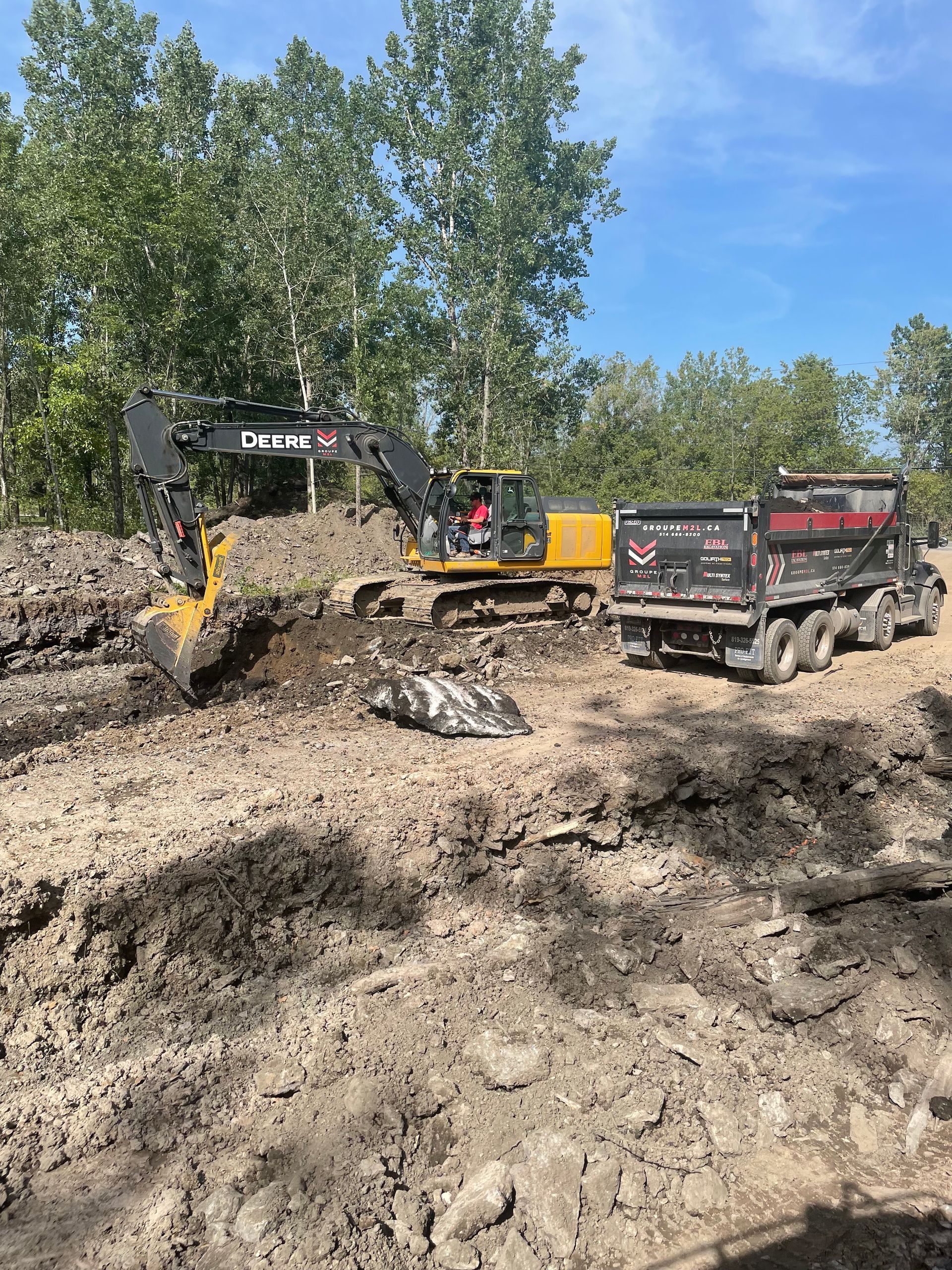 Un bulldozer et un camion-benne traversent un champ de terre.