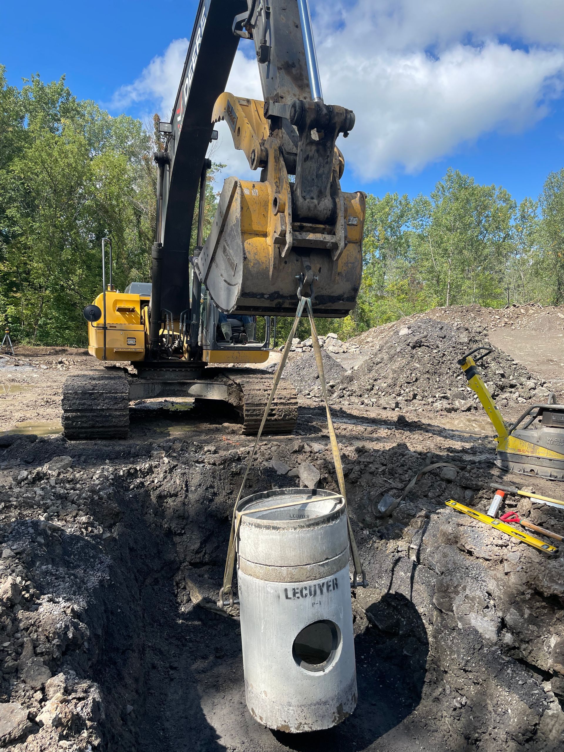 Une excavatrice soulève un tuyau en béton dans la terre.