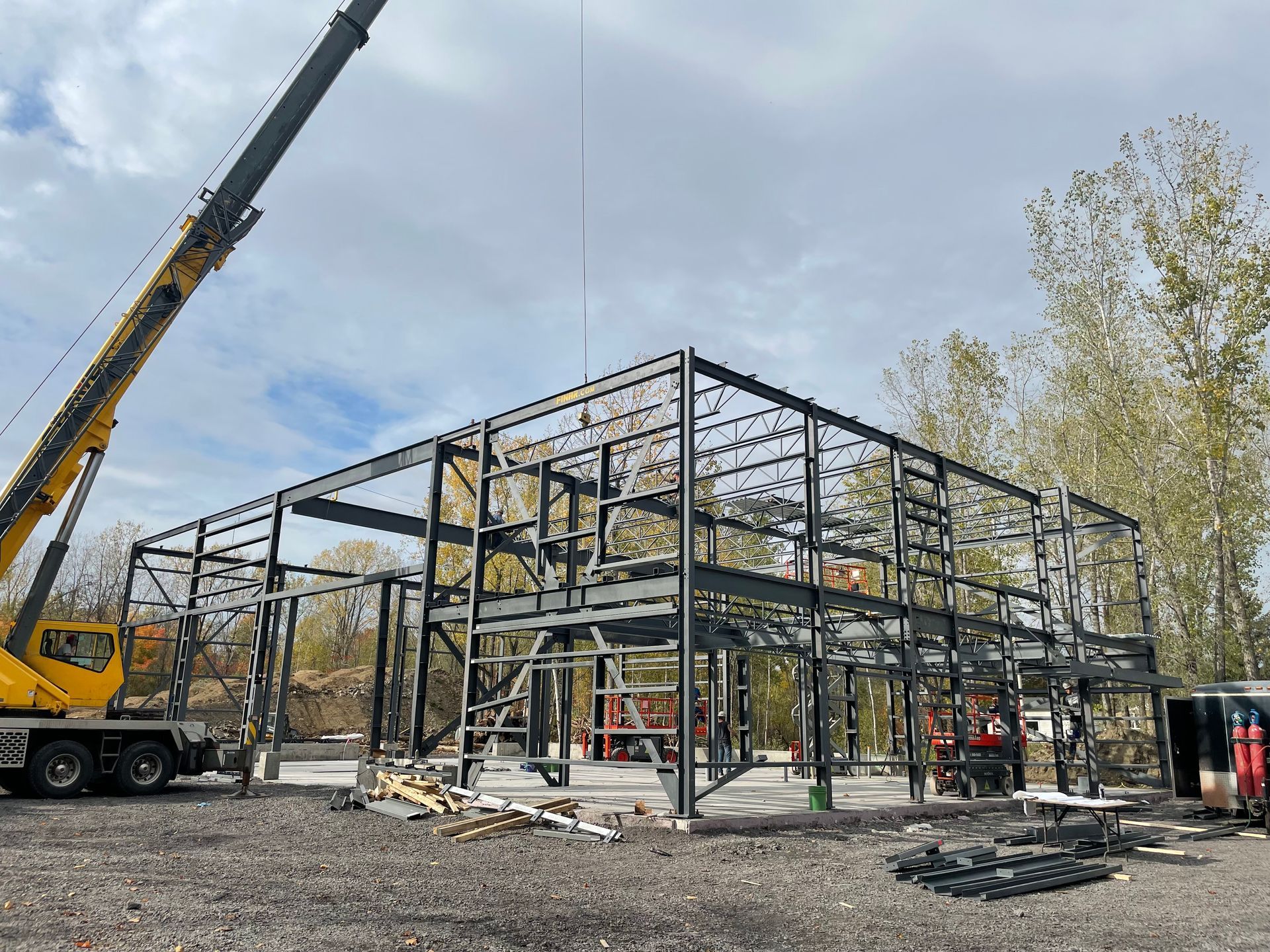 Une grue soulève la charpente métallique d'un bâtiment.