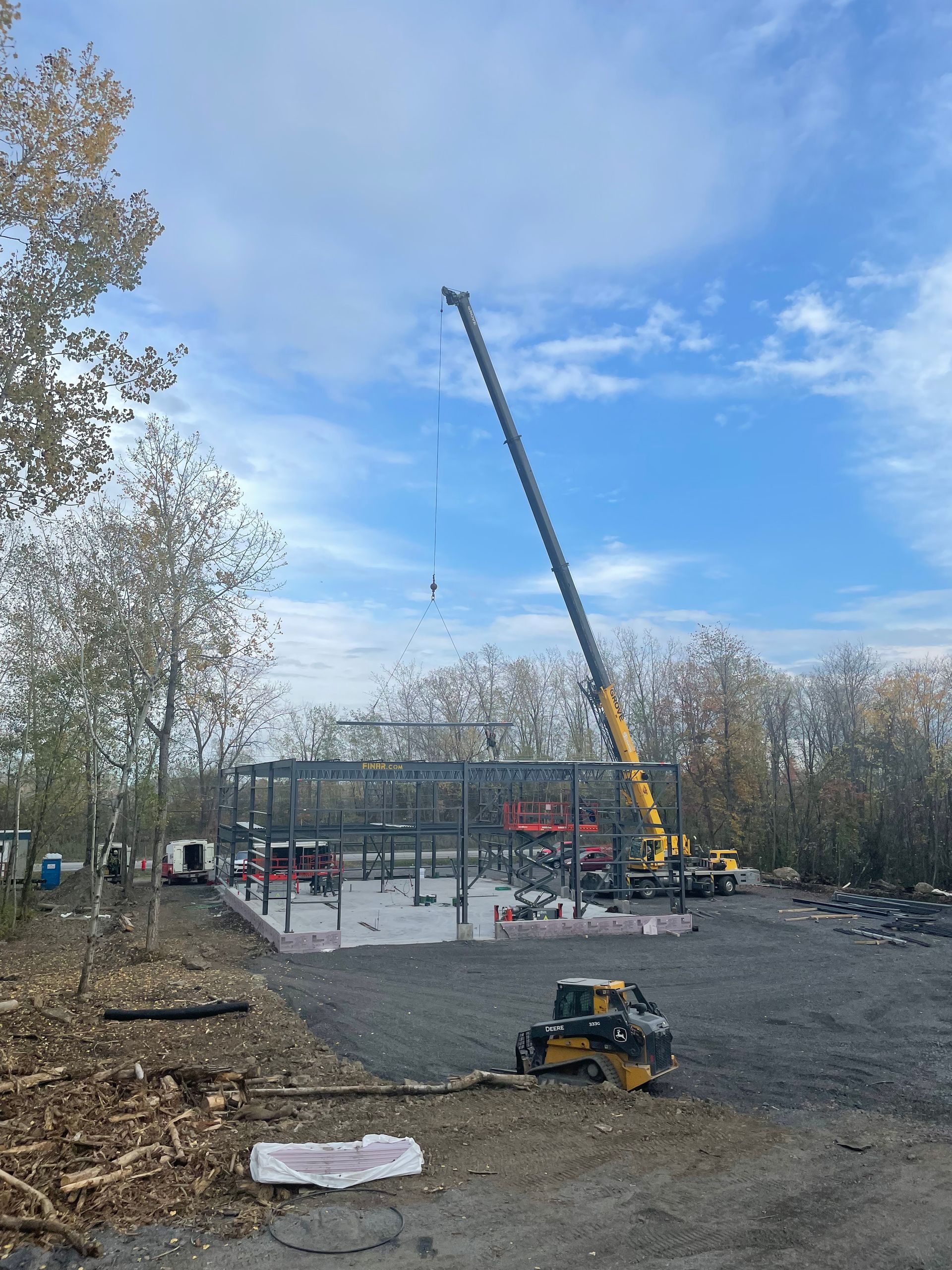 Une grande grue soulève une structure métallique dans un parking.