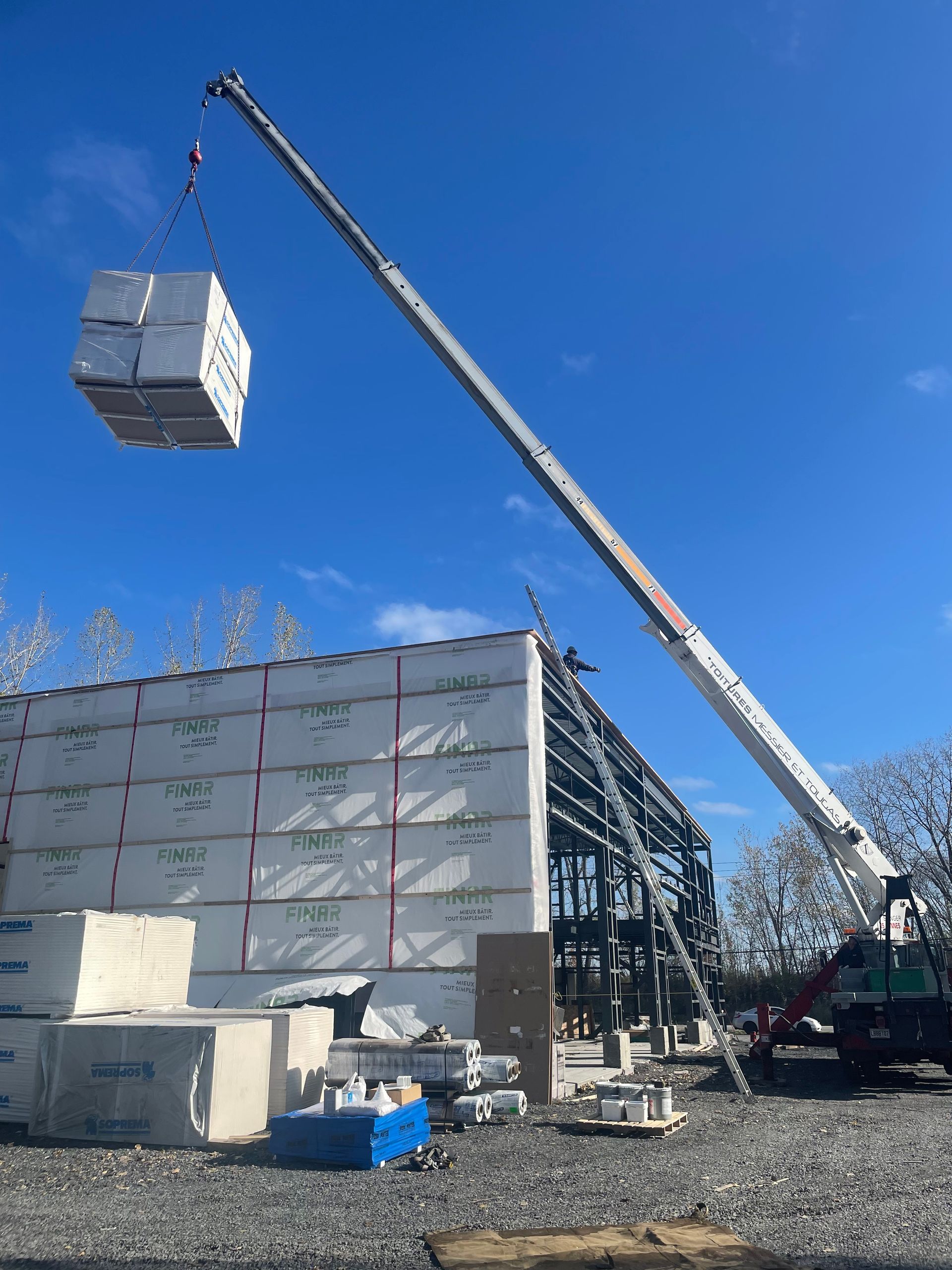 Une grande grue soulève une grande boîte dans les airs.