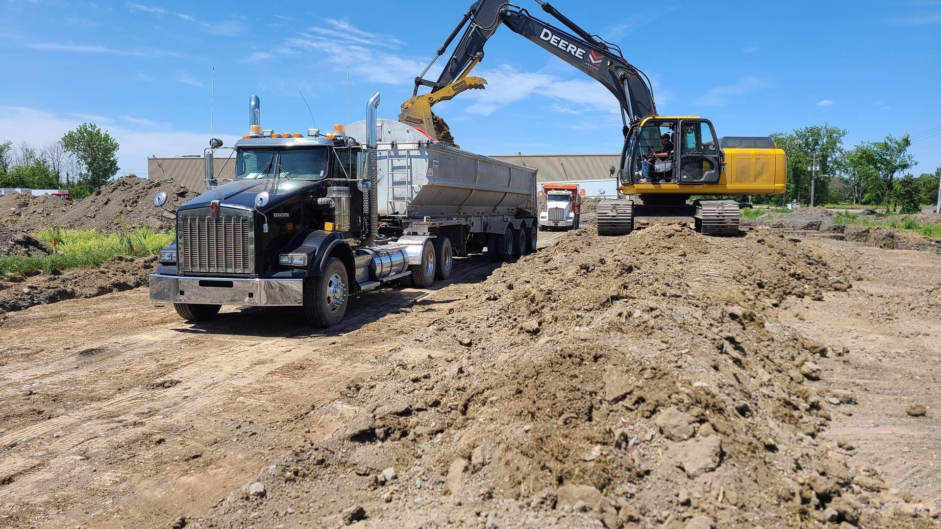 Un camion-benne est chargé de terre par une excavatrice.
