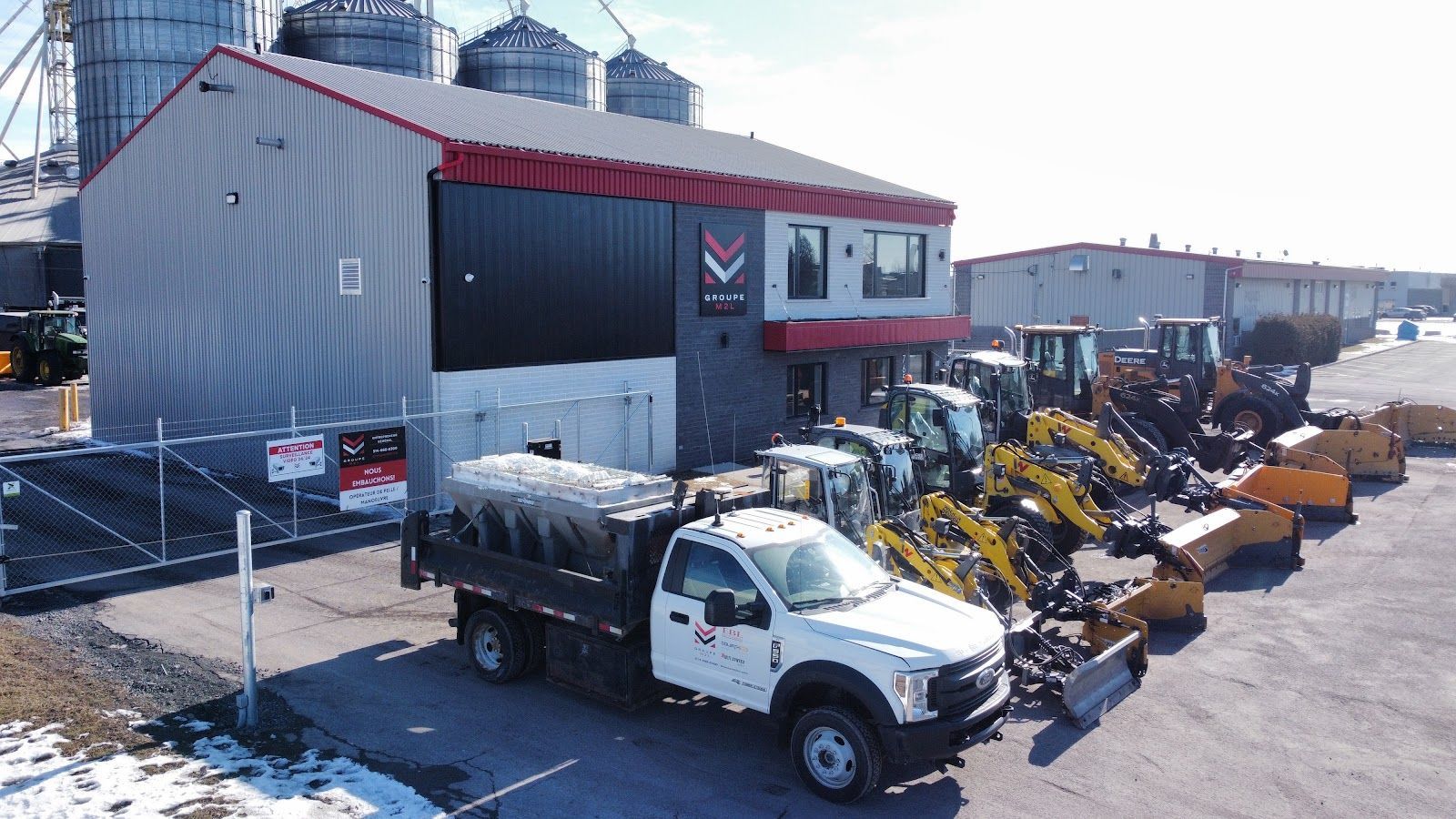 Un camion blanc est garé devant un immeuble avec des excavatrices