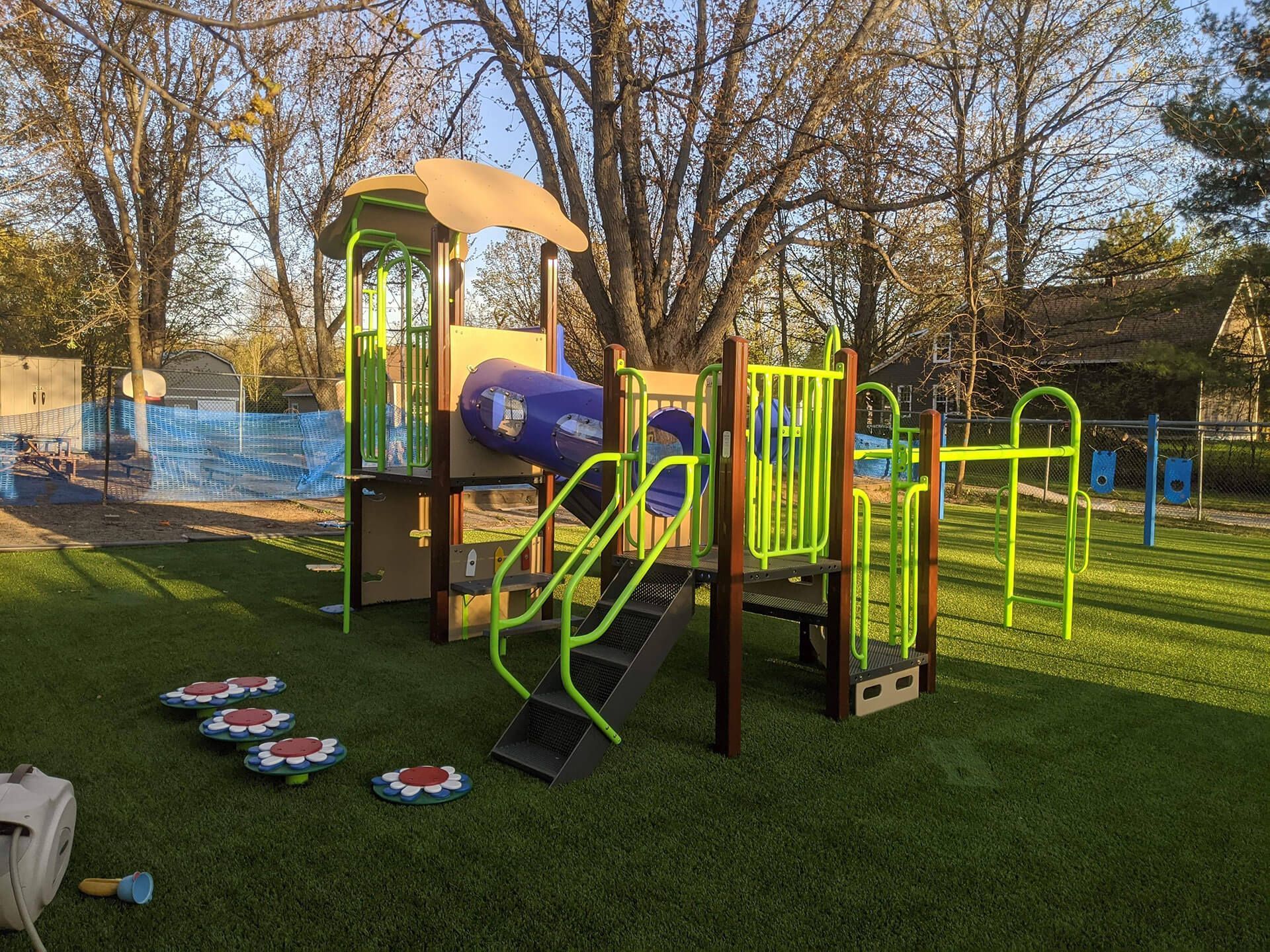 Un terrain de jeu coloré se trouve au sommet d'un champ verdoyant.