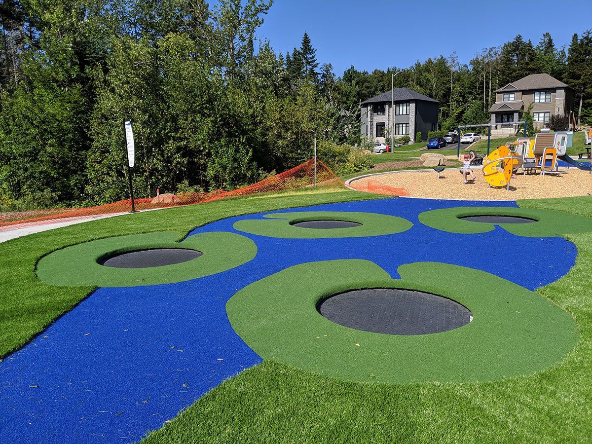 Une aire de jeux avec un trampoline au milieu.