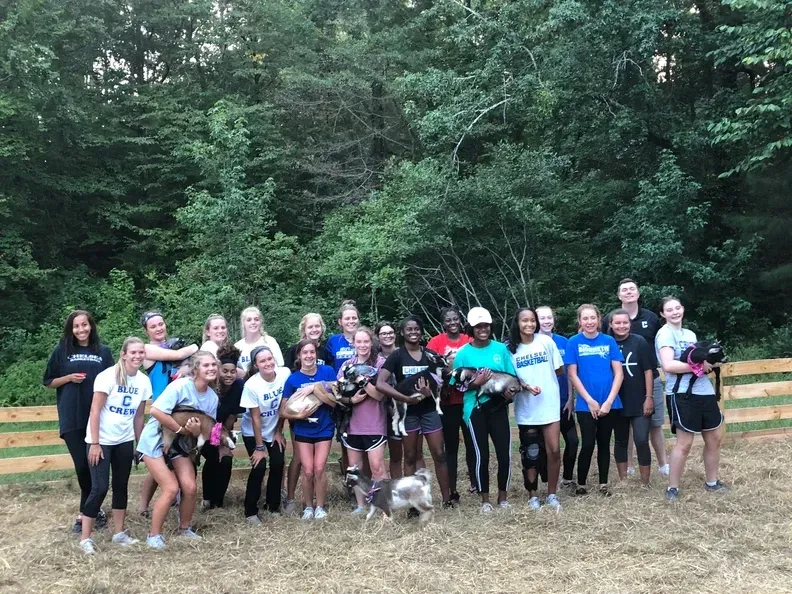 A group of people are posing for a picture in a field with trees in the background.