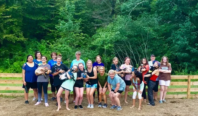 A group of people are posing for a picture in front of a wooden fence.