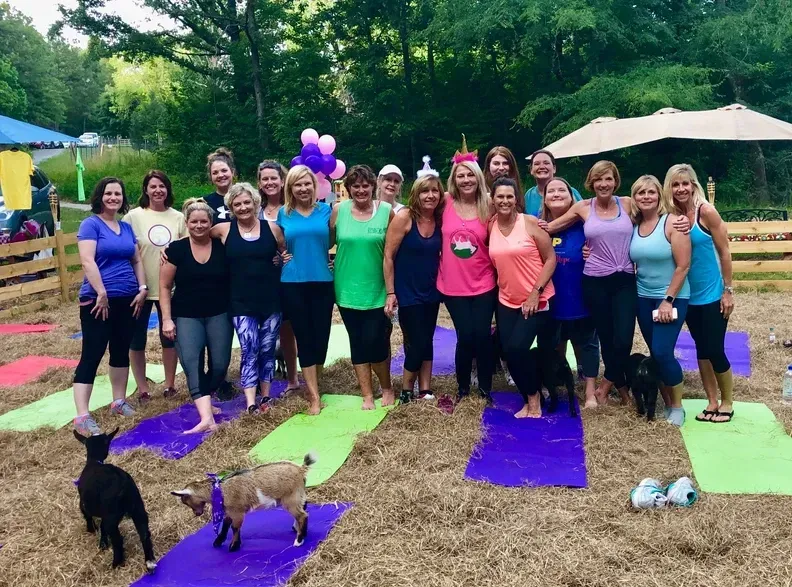 A group of women are posing for a picture while standing on yoga mats.